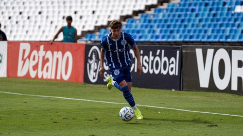 Free Focused soccer player dribbling the ball during a match. Energetic scene with empty stadium stands. Stock Photo