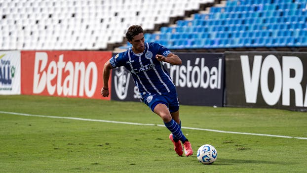 Soccer player dribbling the ball during a match on a sunny day.