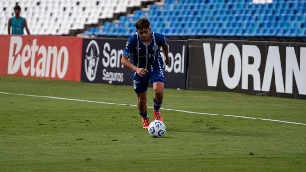 Soccer player dribbling a ball in a stadium during match, focused action.