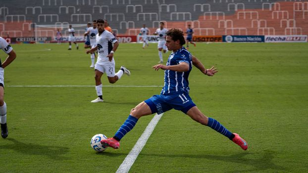 Dynamic soccer match featuring players in blue and white uniforms during a sunny day.