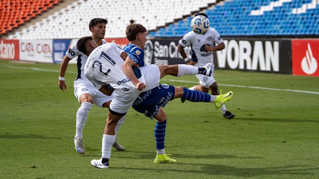 Dramatic action during a soccer match with players tackling for ball possession.
