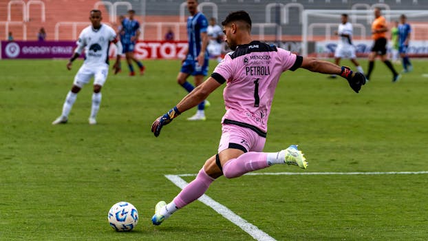 Dynamic image of a soccer goalie kicking the ball during a match in a stadium.