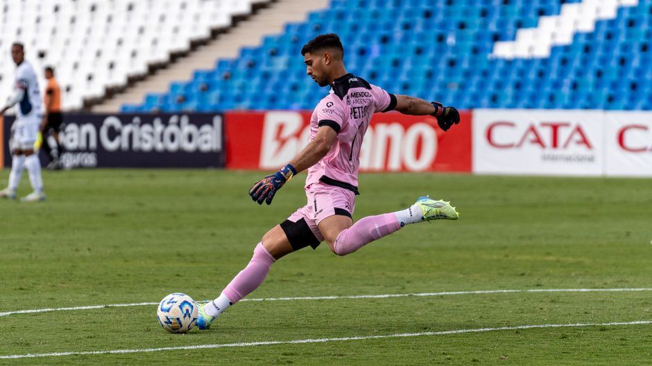 Dynamic shot of a goalkeeper in pink uniform kicking a soccer ball.