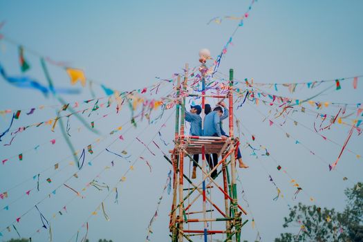 People assembling flag tower in a vibrant outdoor festival setting with colorful flags.