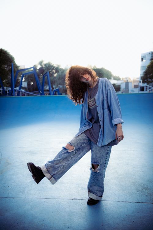 Free Casually dressed teenager poses in denim attire at an empty urban skate park during the day. Stock Photo
