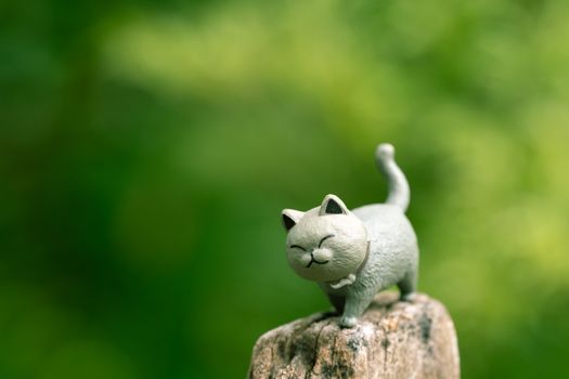 Charming cat sculpture perched on a rock with vibrant greenery backdrop.