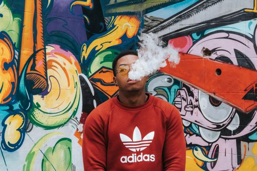 Dynamic street art backdrop with individual exhaling smoke in Richmond, VA.