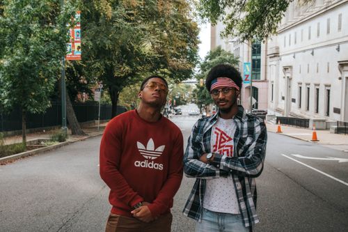 Free Two fashionable men posing outdoors on a city street with trees and buildings. Stock Photo