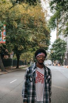 一个穿着休闲服的年轻人自信地走在弗吉尼亚州里士满绿树成荫的城市街道上