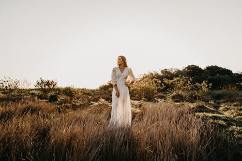 잔디 필드에 서있는 흰 드레스 여자
