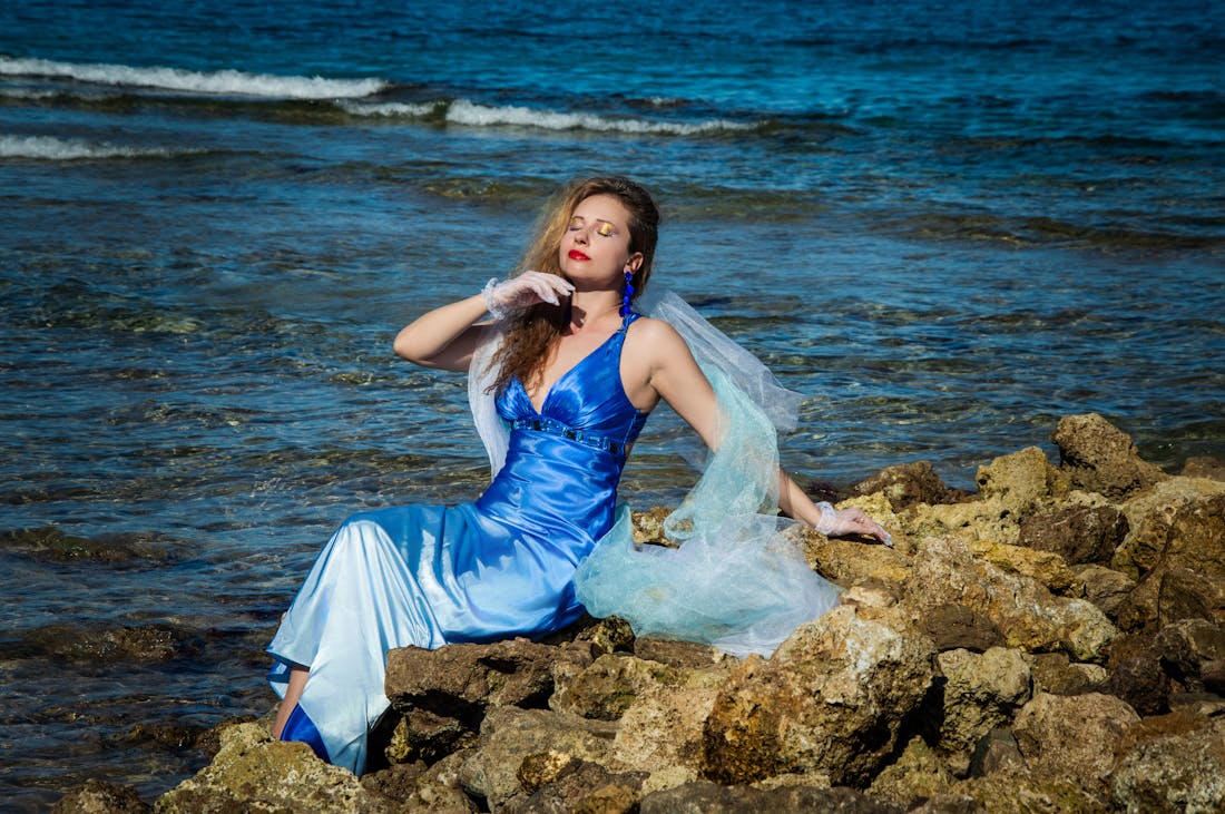 Woman posing by the sea in a sapphire blue mermaid gown