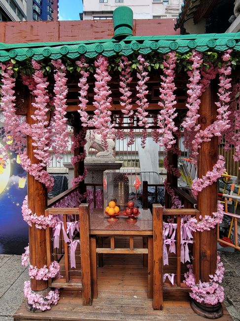 Fotomural Encantador pabellón de madera adornado con guirnaldas florales rosas en un vibrante entorno urbano, Hong Kong