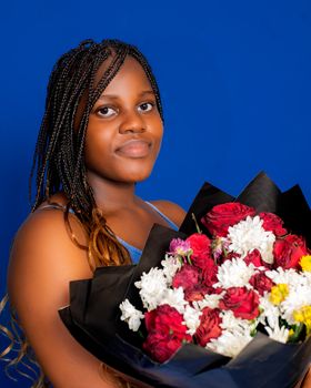 A woman in blue with braided hair holds a vibrant bouquet of red and white flowers. - Fotografer Sidoarjo