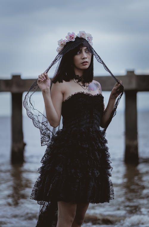 Woman Wearing Black Sweetheart Dress Walking on Seashore