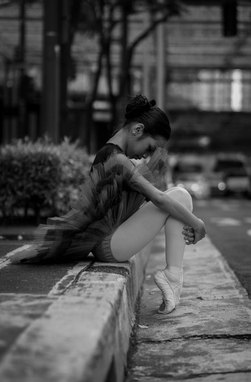 Free A graceful ballerina poses in a thoughtful moment on a city sidewalk. Stock Photo