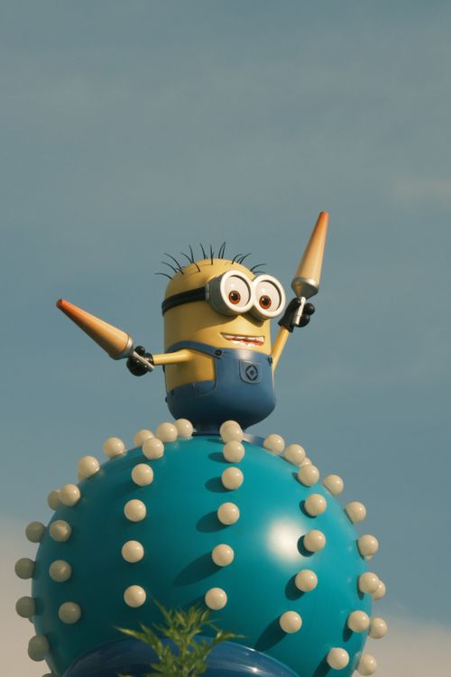 Free Vibrant Minion character statue atop a whimsical spiked orb under a clear blue sky. Stock Photo