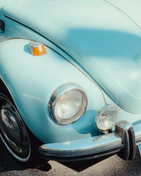 Close-up of a vintage blue Volkswagen Beetle headlight and fender, classic car style.