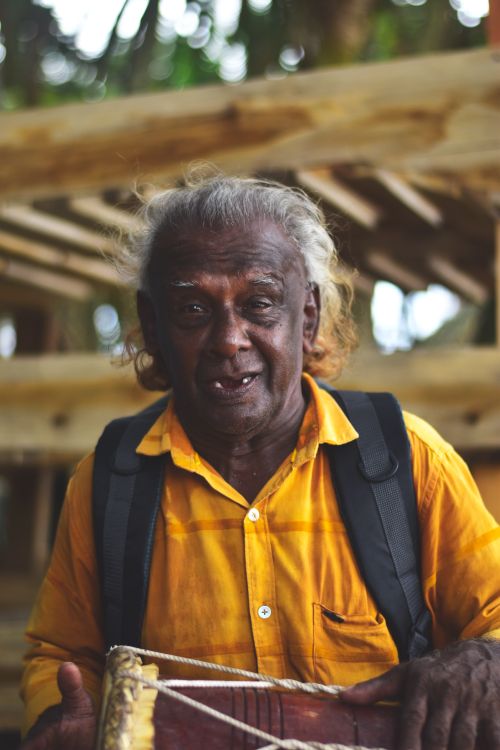 Free Portrait of an elderly South Asian man playing a traditional drum outdoors in Sri Lanka. Stock Photo