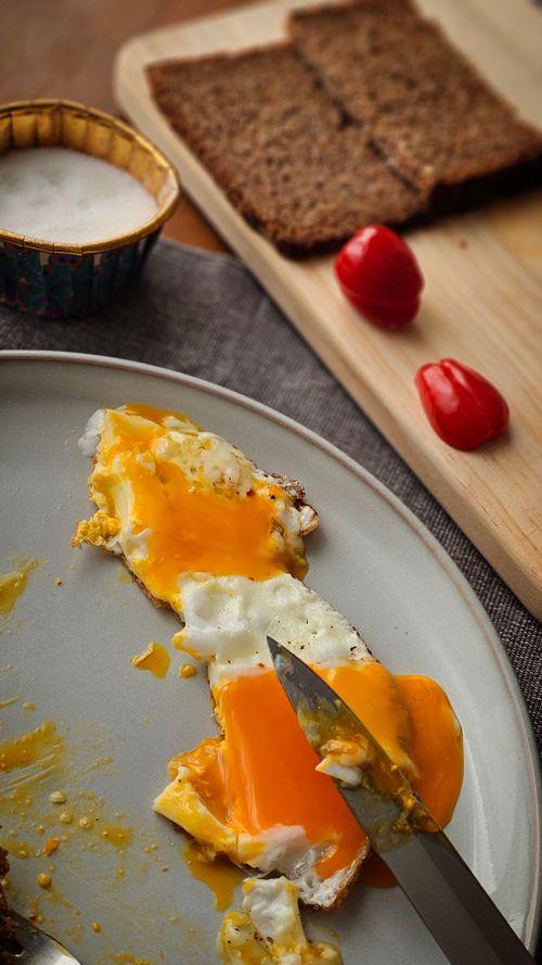 Free Appetizing sunny side up eggs with toast and tomatoes on a breakfast table. Stock Photo