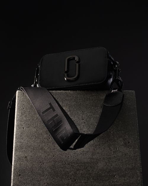 Free Elegant black handbag displayed on a concrete pedestal in a dark, modern setting. Stock Photo
