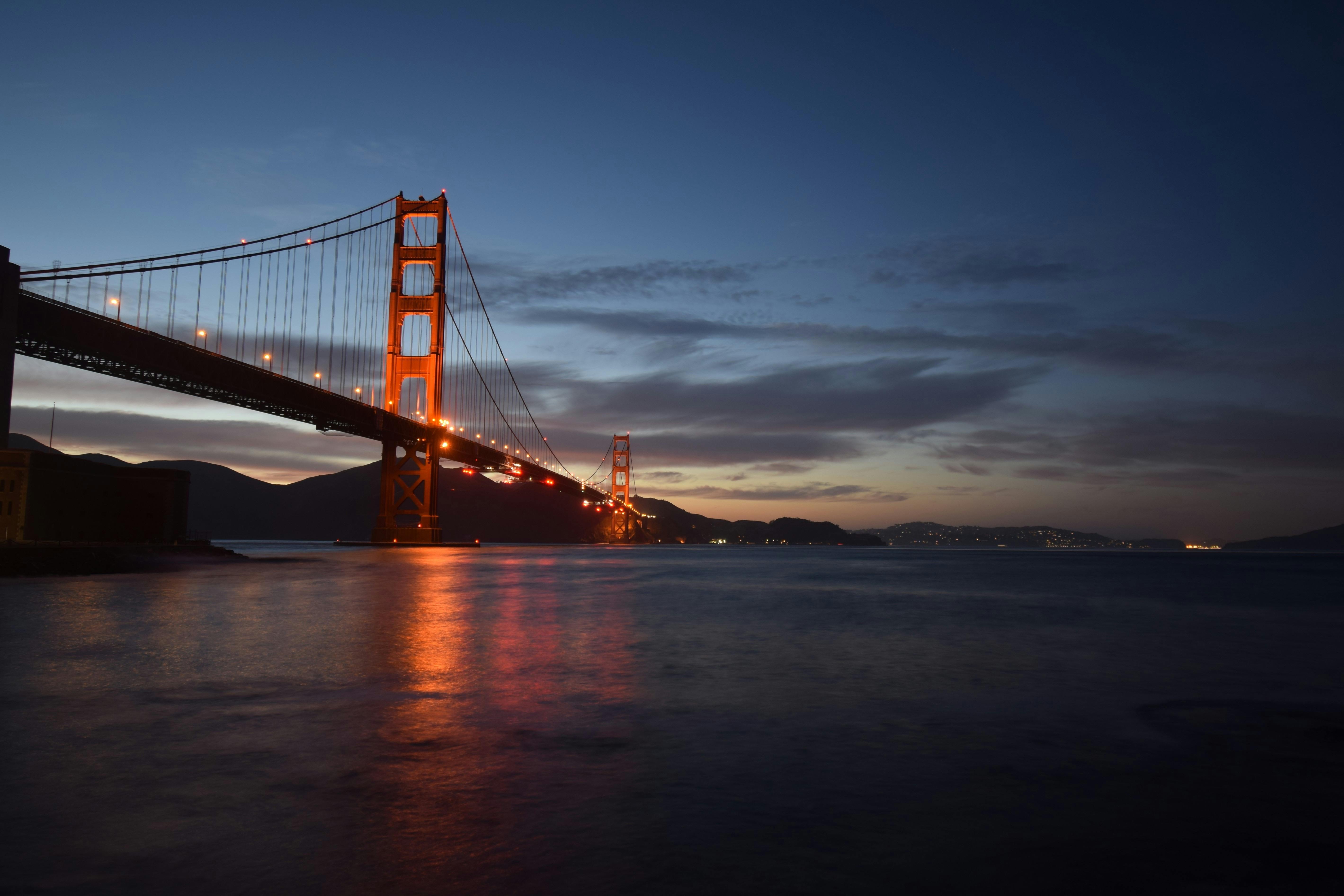Serene view of the illuminated Golden Gate Bridge at twilight with reflection in the water.