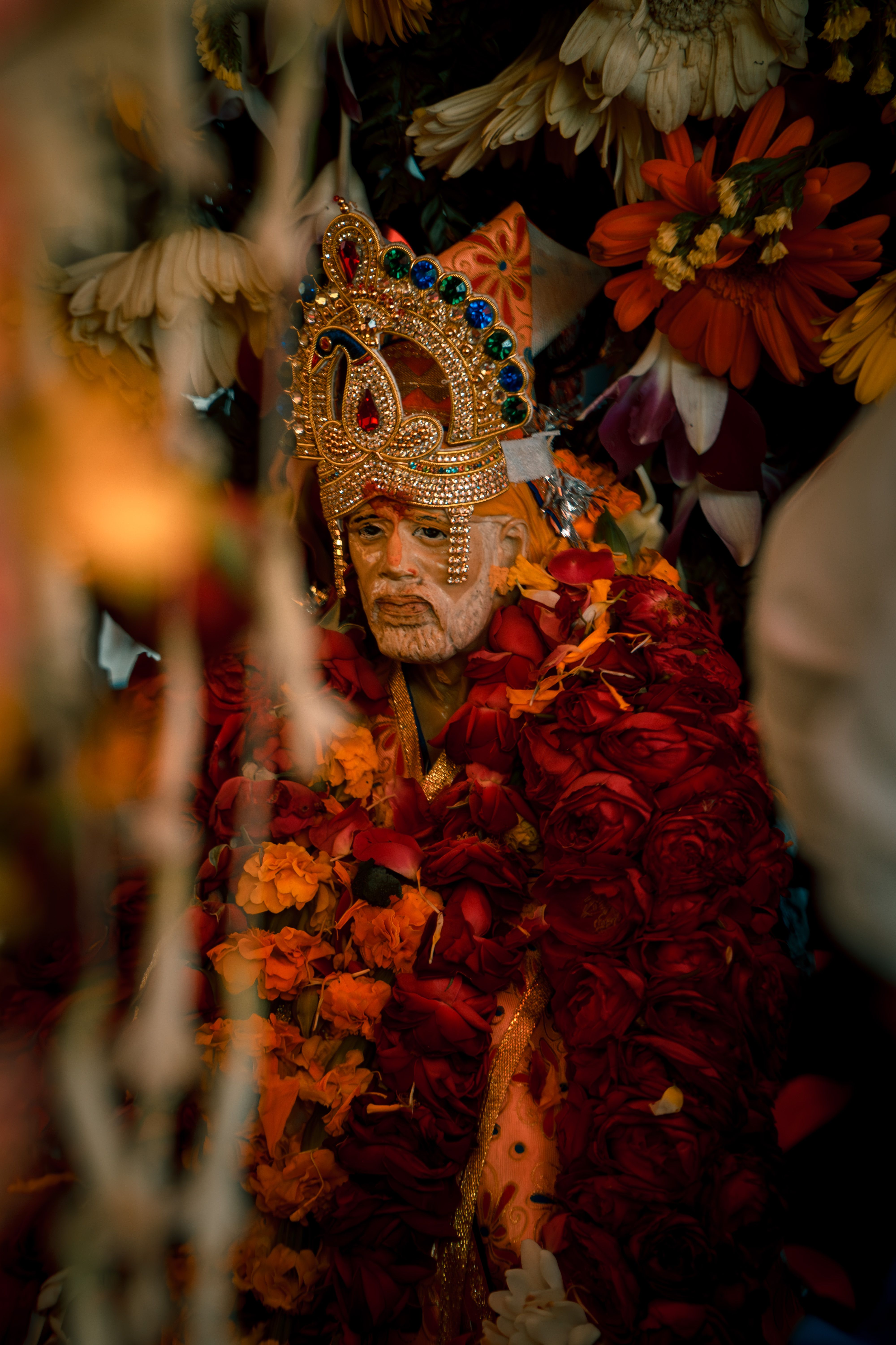 A vibrant deity statue adorned with colorful flowers and intricate jewelry in a cultural setting.
