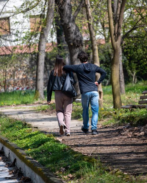 Free A couple enjoying a leisurely walk in a charming park during spring, surrounded by trees. Stock Photo
