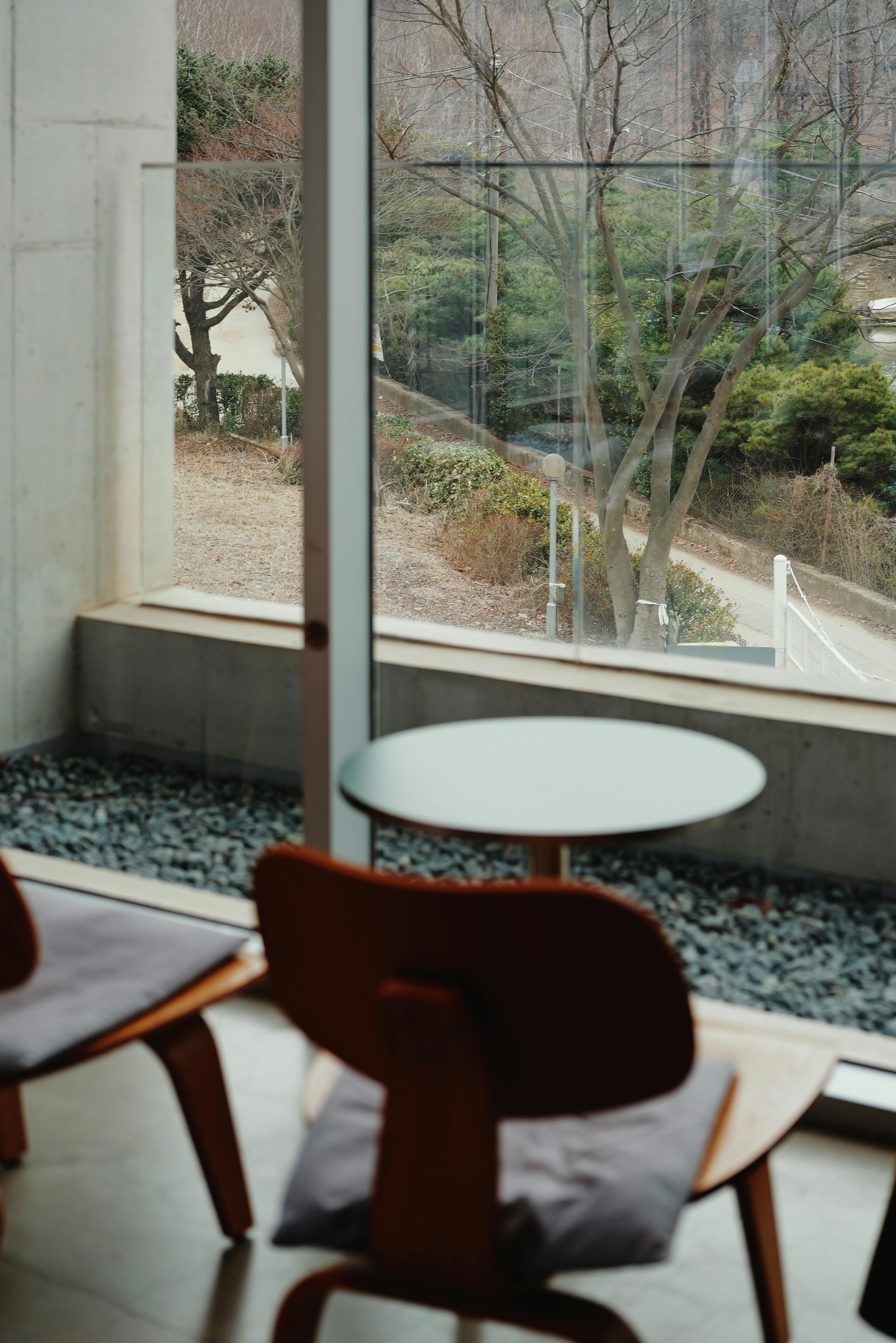 Cozy indoor seating area with views of trees through a large glass window.