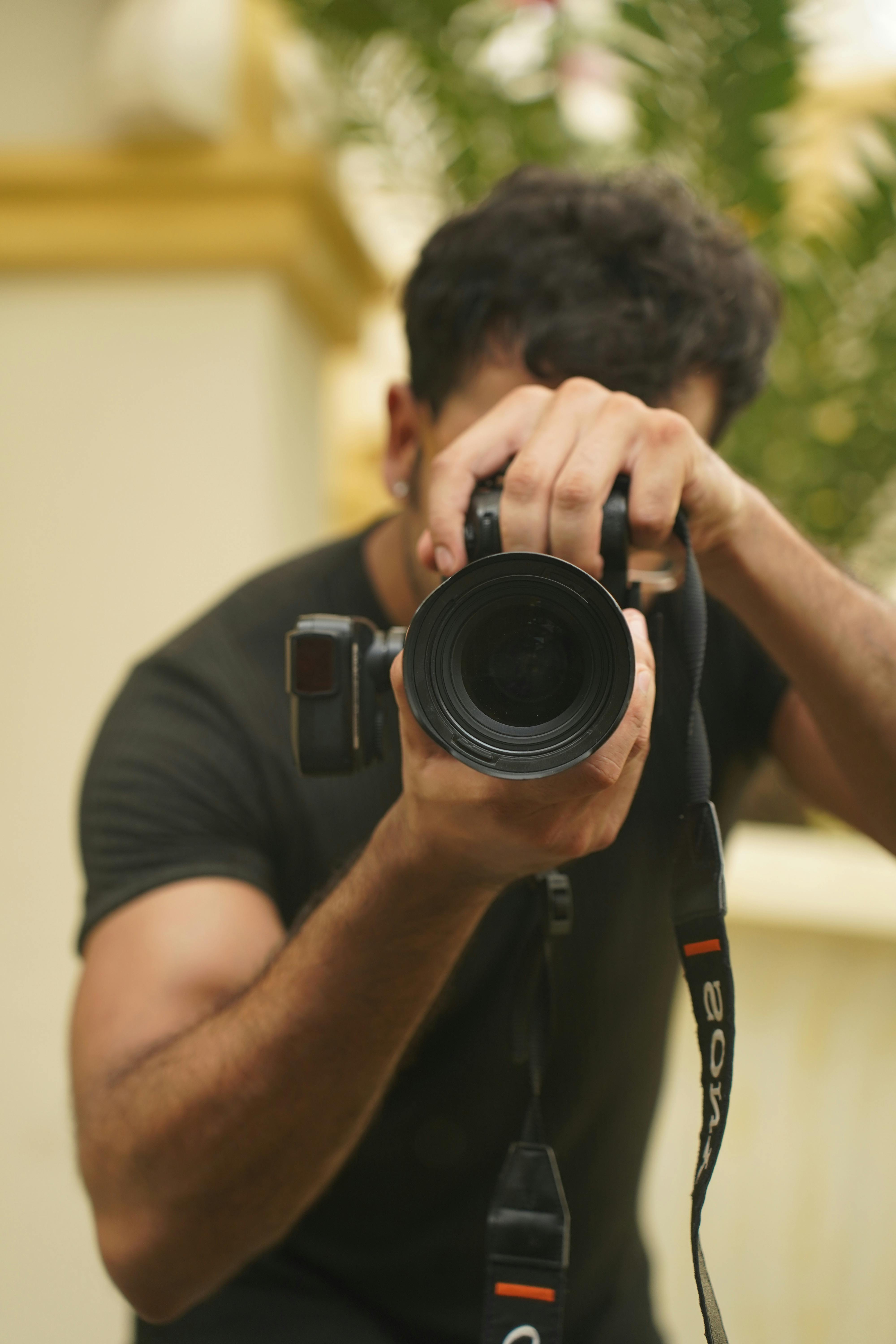 A close-up shot of a male photographer capturing an image outdoors.