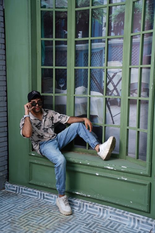 Free Stylish male model in sunglasses posing casually by a window in Lahore, Pakistan. Stock Photo