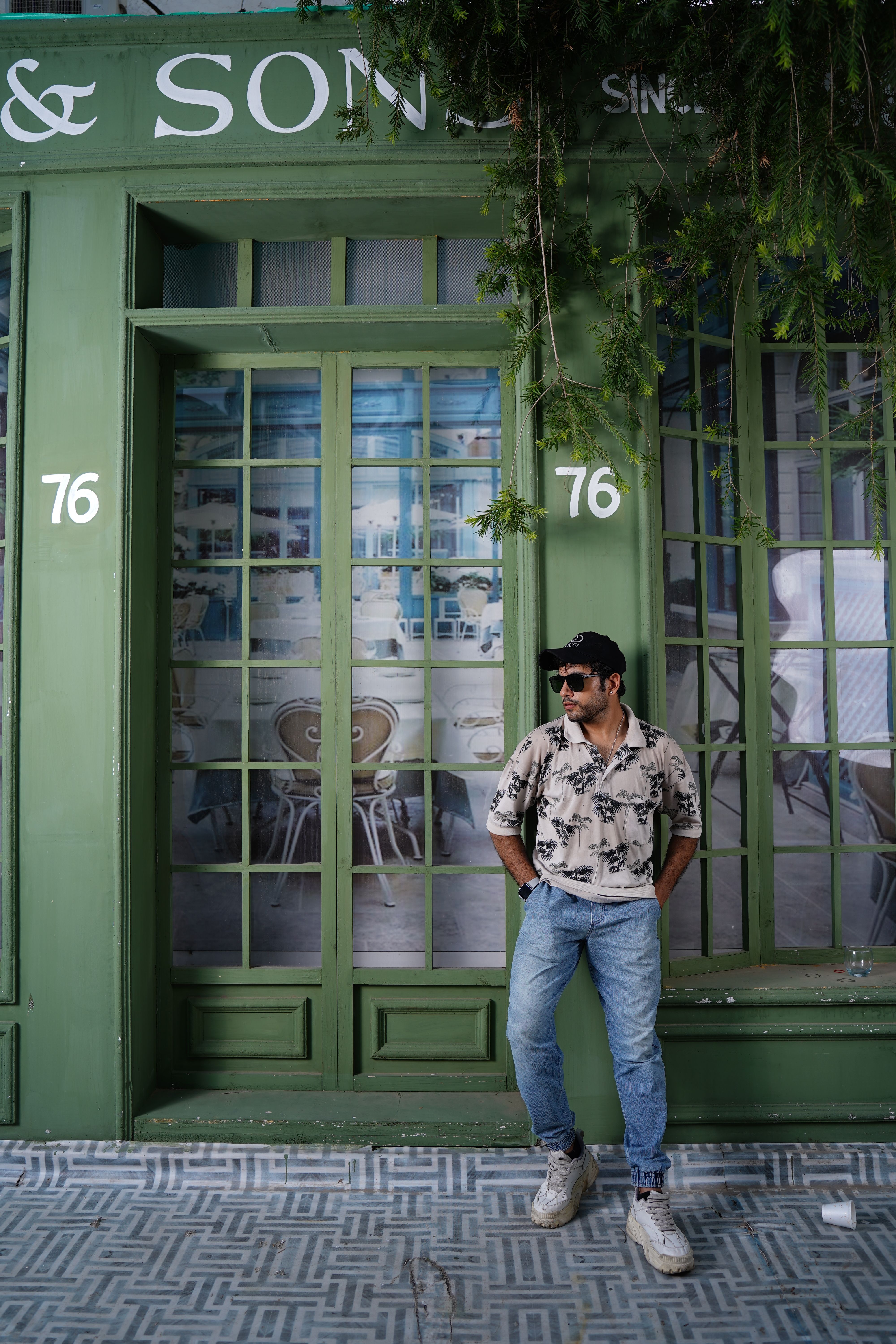 A fashion-forward individual poses stylishly against a retro storefront in Lahore.