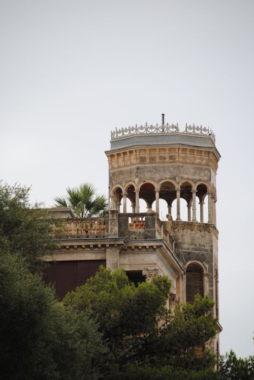 Free Elegant arched tower in Nice, France framed by lush greenery and overcast sky. Stock Photo