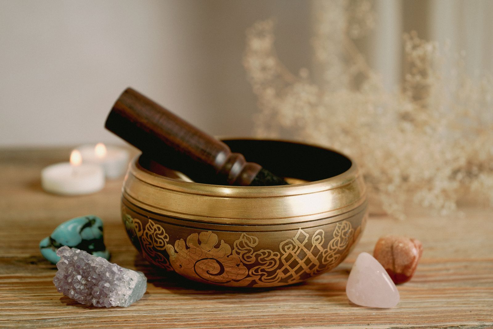 A brass singing bowl for a sound healing session in Dubai, with a wooden mallet, crystals and candles
