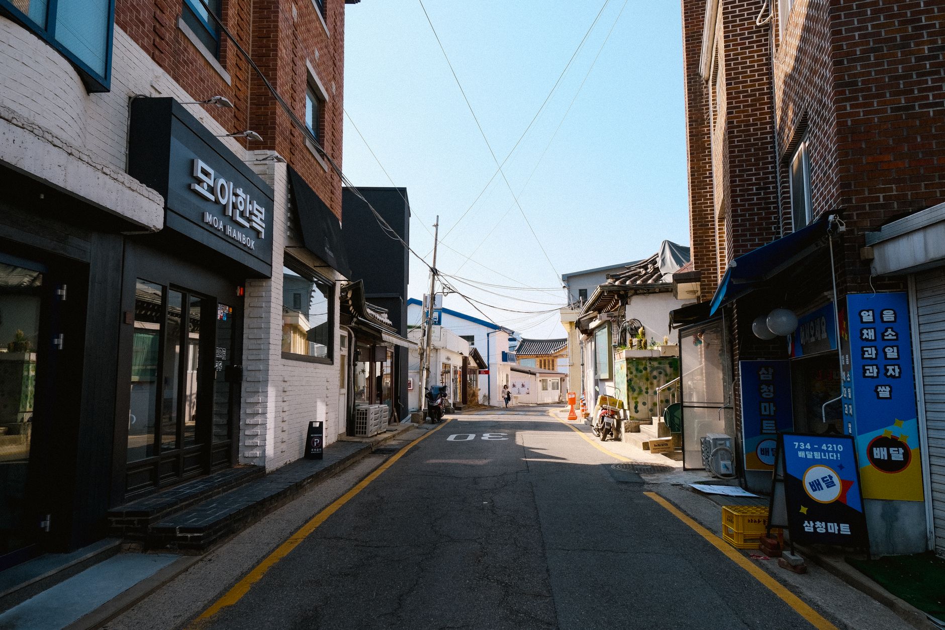 Charming Korean street featuring traditional and modern architecture on a sunny day.