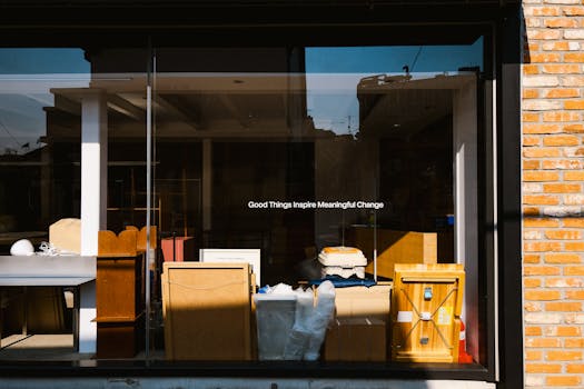 A storefront window featuring the quote 'Good Things Inspire Meaningful Change' with furniture and decorations inside.