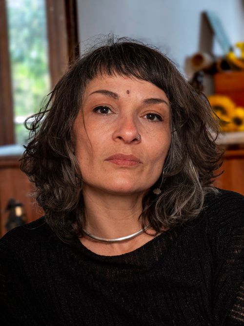 Free Close-up portrait of a woman with curly hair and nose ring indoors, looking thoughtful. Stock Photo