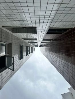 Symmetrical view of tall buildings with sky background, creating an abstract urban feel.