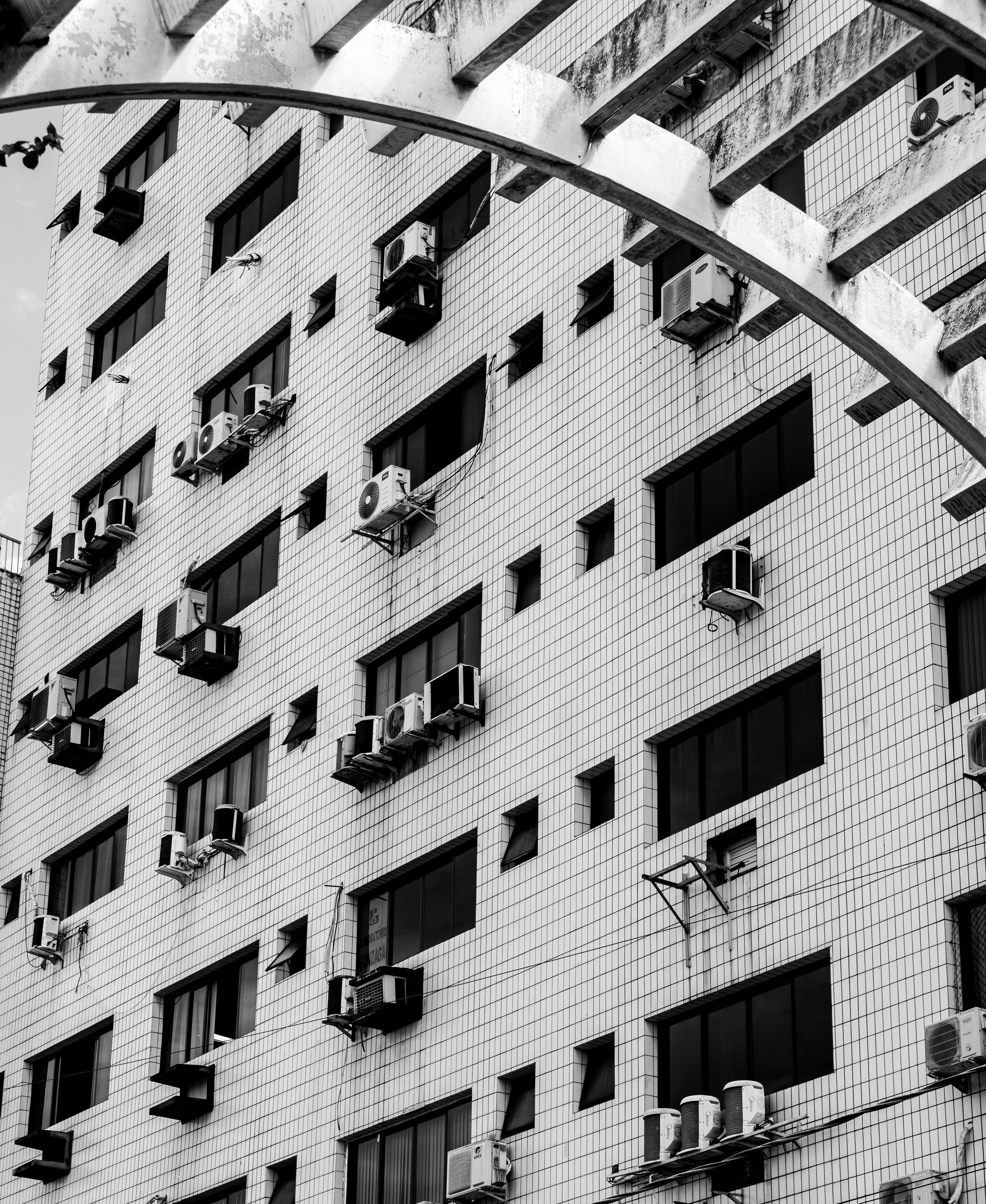 Black and white photo of a tiled building facade with air conditioners in Praia Grande, Brazil.