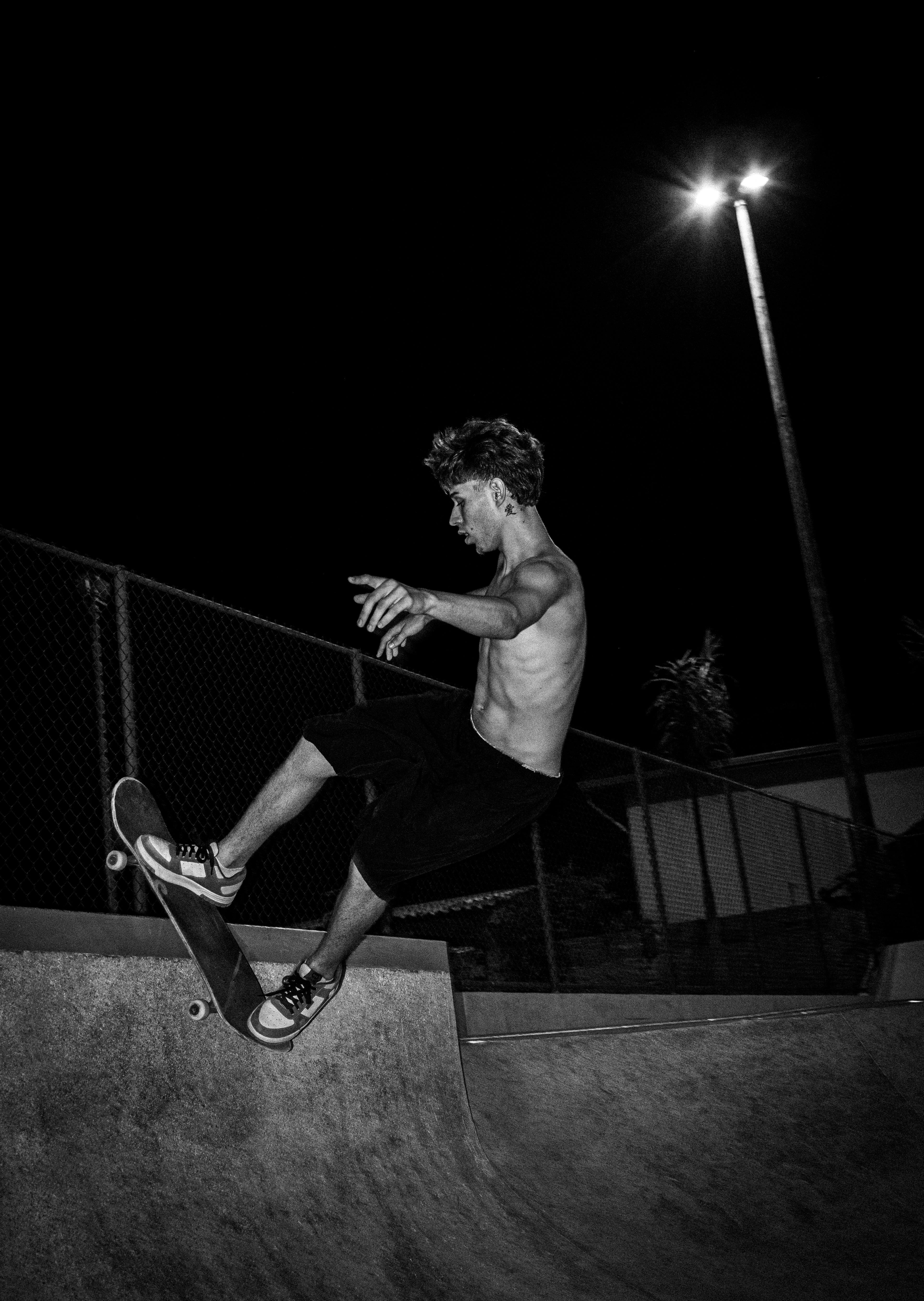 Captivating black and white shot of a skateboarder in action at night in Praia Grande, Brazil.
