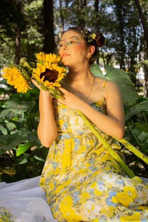 Free Young woman enjoying sunflowers in a bright, lush outdoor setting. Stock Photo