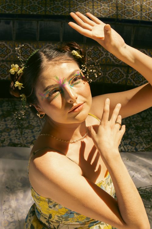 Free A woman with artistic floral makeup poses under sunlight, showcasing a garden theme. Stock Photo