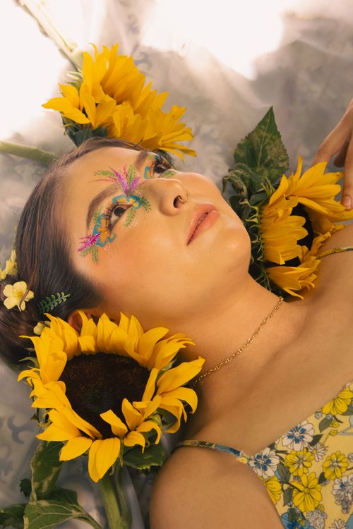 Free Artistic portrait of a woman with colorful makeup and sunflowers, exuding a vibrant, summer feel. Stock Photo