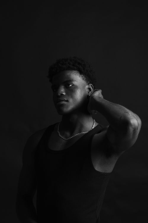 Free Monochrome portrait of a man in a contemplative pose with a dark background. Stock Photo