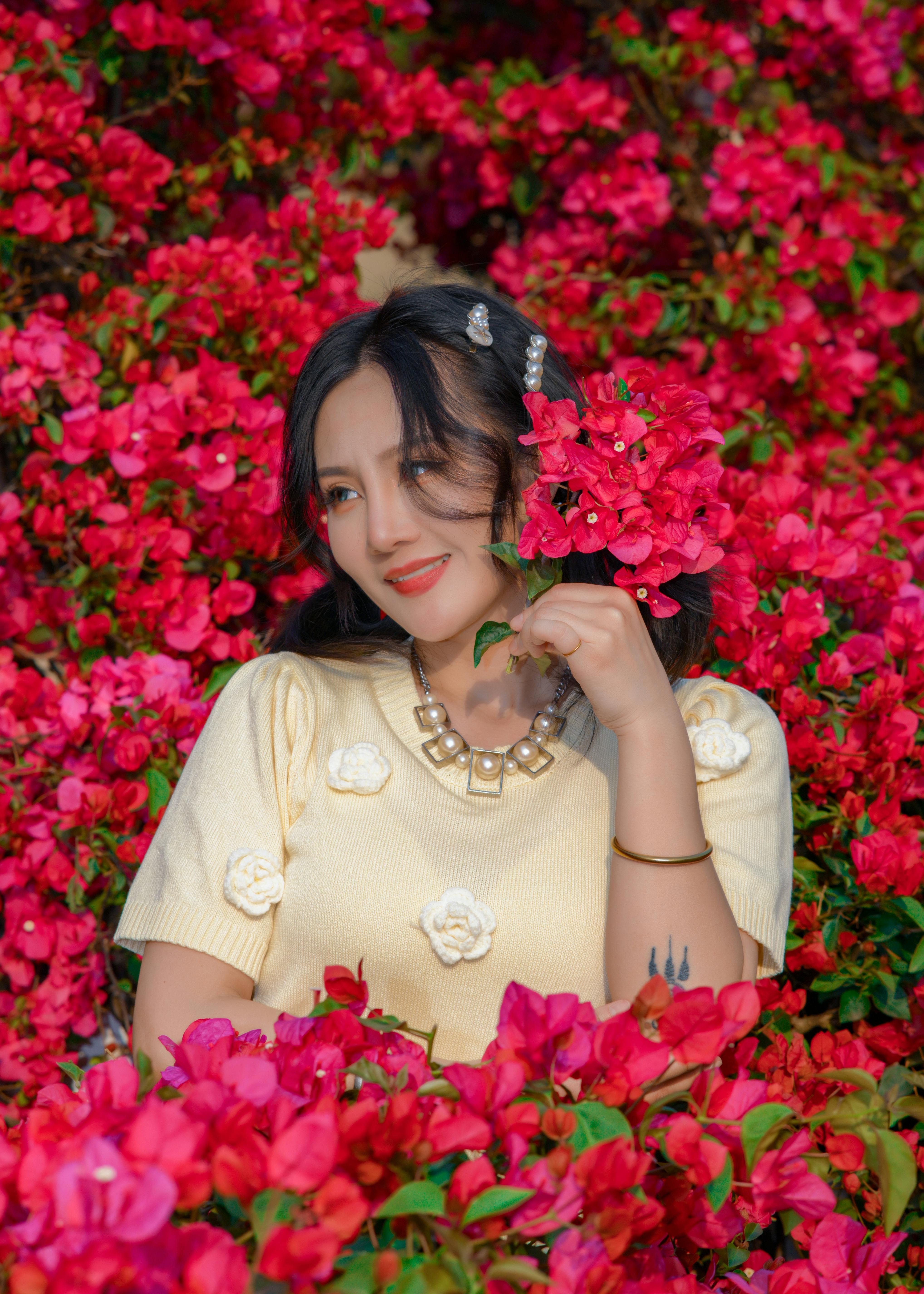 Portrait of a woman surrounded by vibrant pink bougainvillea flowers outdoors.