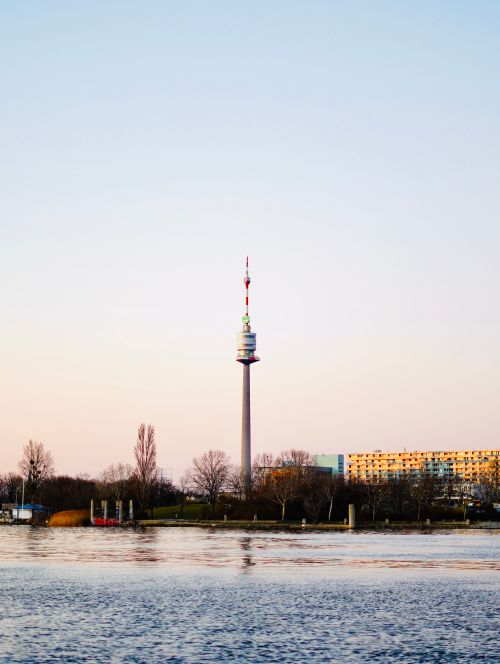 Free Serene twilight view of the iconic Donauturm in Vienna, Austria with calm waters in foreground. Stock Photo