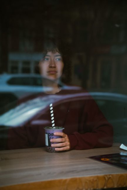 A person enjoys bubble tea while sitting in a cafe, seen through the window in Gaithersburg, MD.