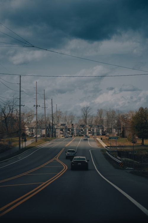 Free Scenic view of a suburban street in Clarksburg, Maryland, capturing vehicles on a road under an overcast sky. Stock Photo