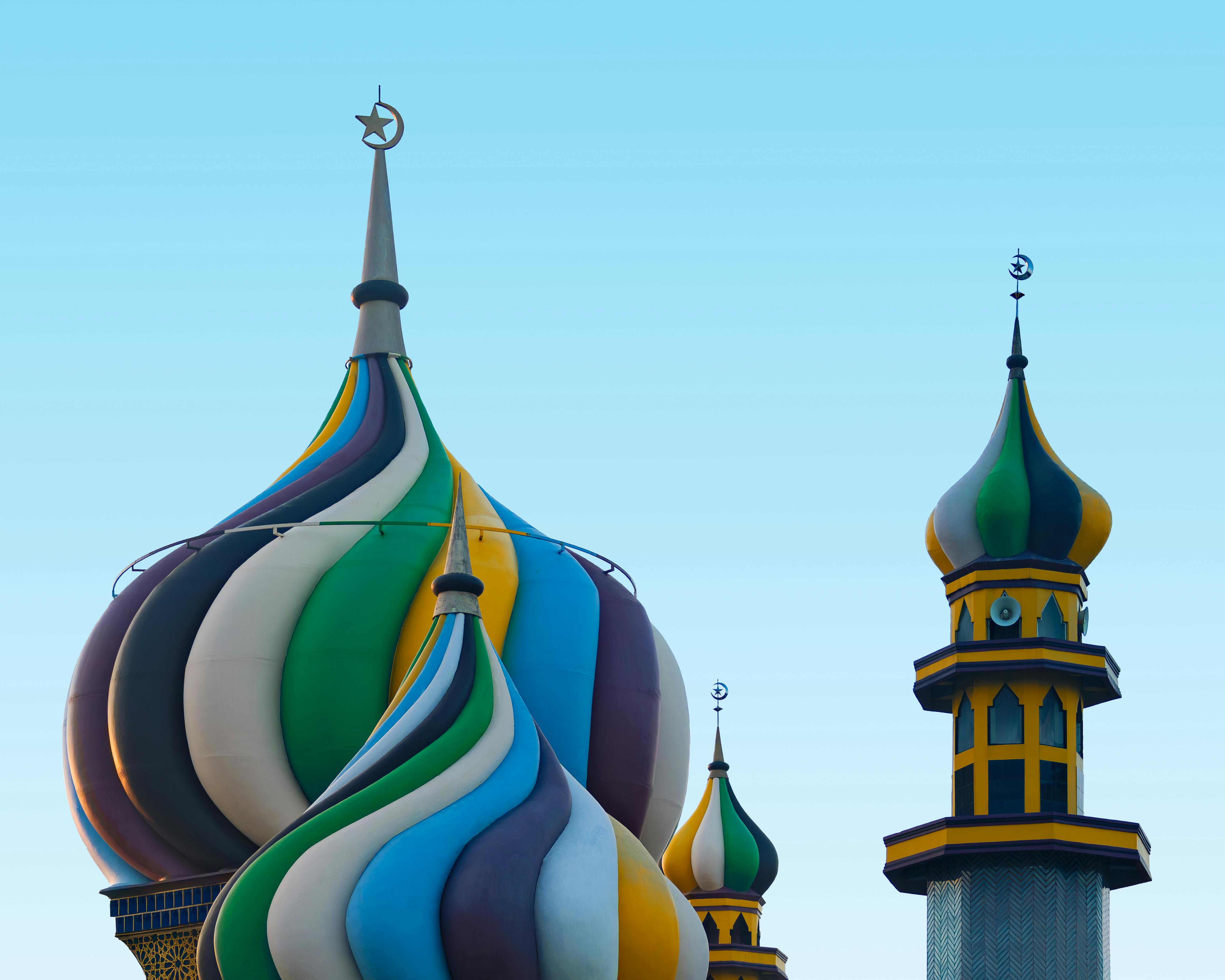 Vibrant mosque domes and minarets against a clear sky in Banten, Indonesia.