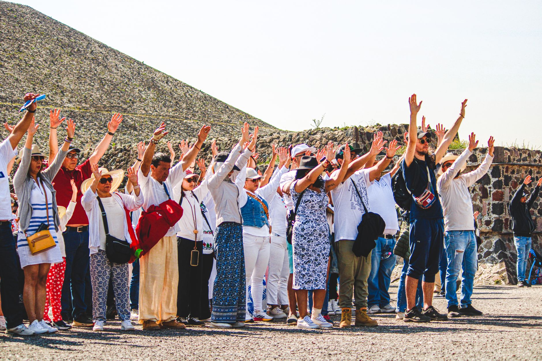 A group of tourists raising hands at the Pyramids of Teotihuacán, Mexico.