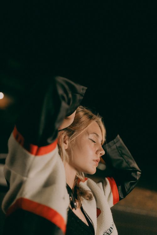 Free A young woman stands outdoors at night in a reflective pose, embodying calm and introspection. Stock Photo